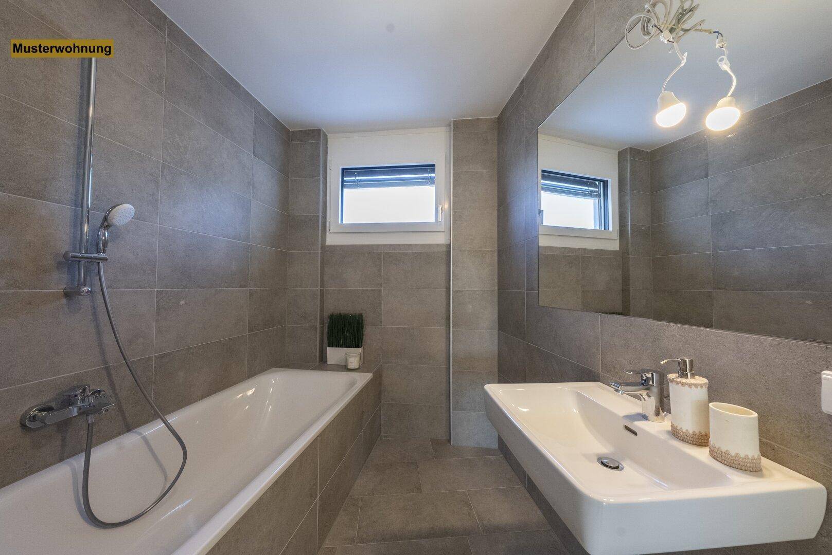 Zeitgemäßes Badezimmer mit Badewanne, großem Spiegel und Fenster, alles in neutralen Grautönen gehalten.