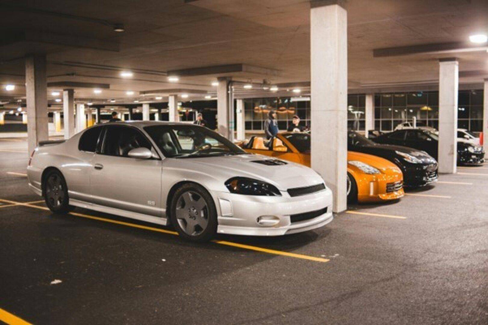 Tiefgarage mit Betonpfeilern und geparkten Autos, beleuchtet von Deckenleuchten.
