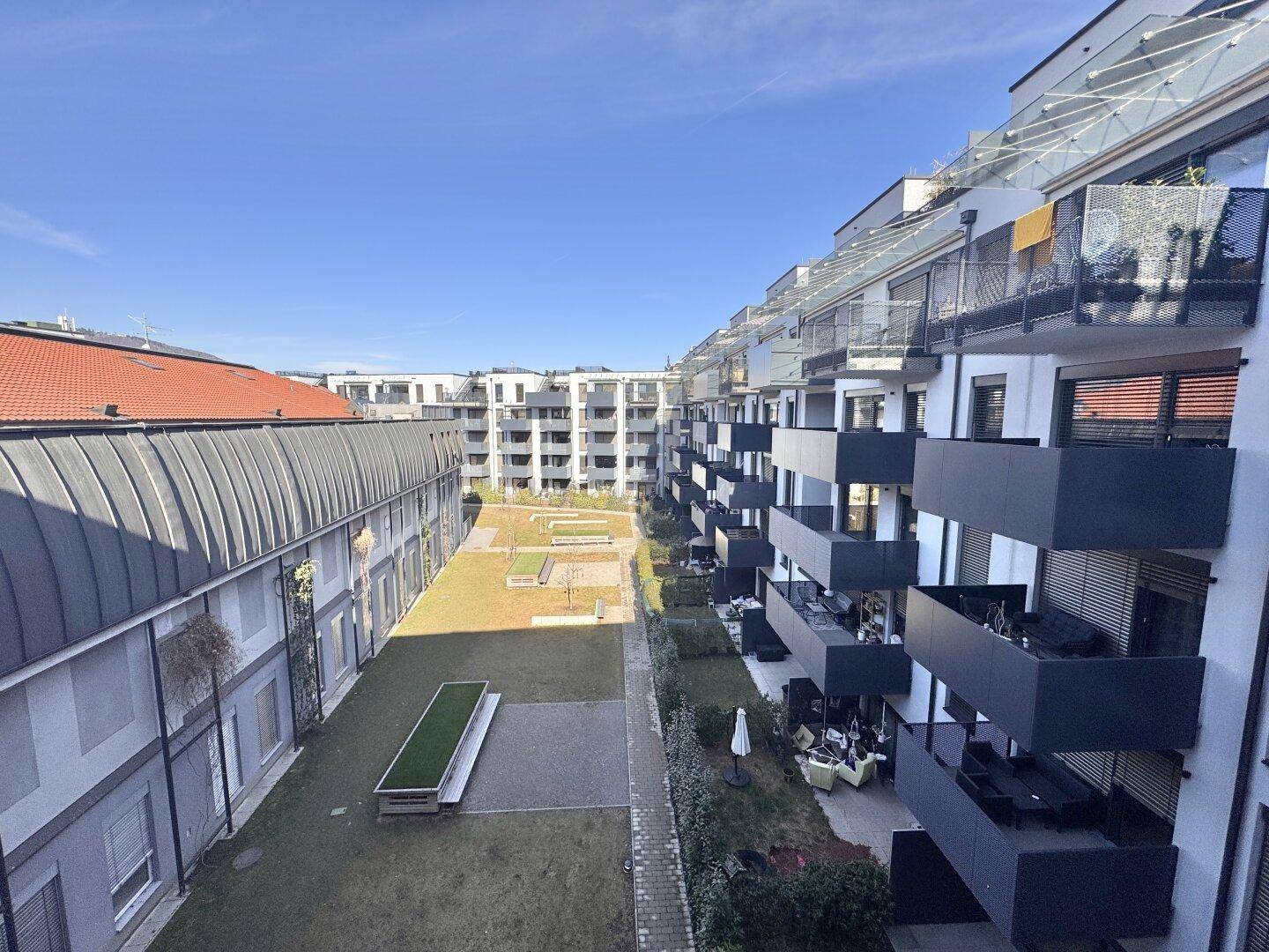 Vogelperspektive auf die moderne Wohnanlage mit großem, gepflegtem Innenhof und vielen Balkonen.