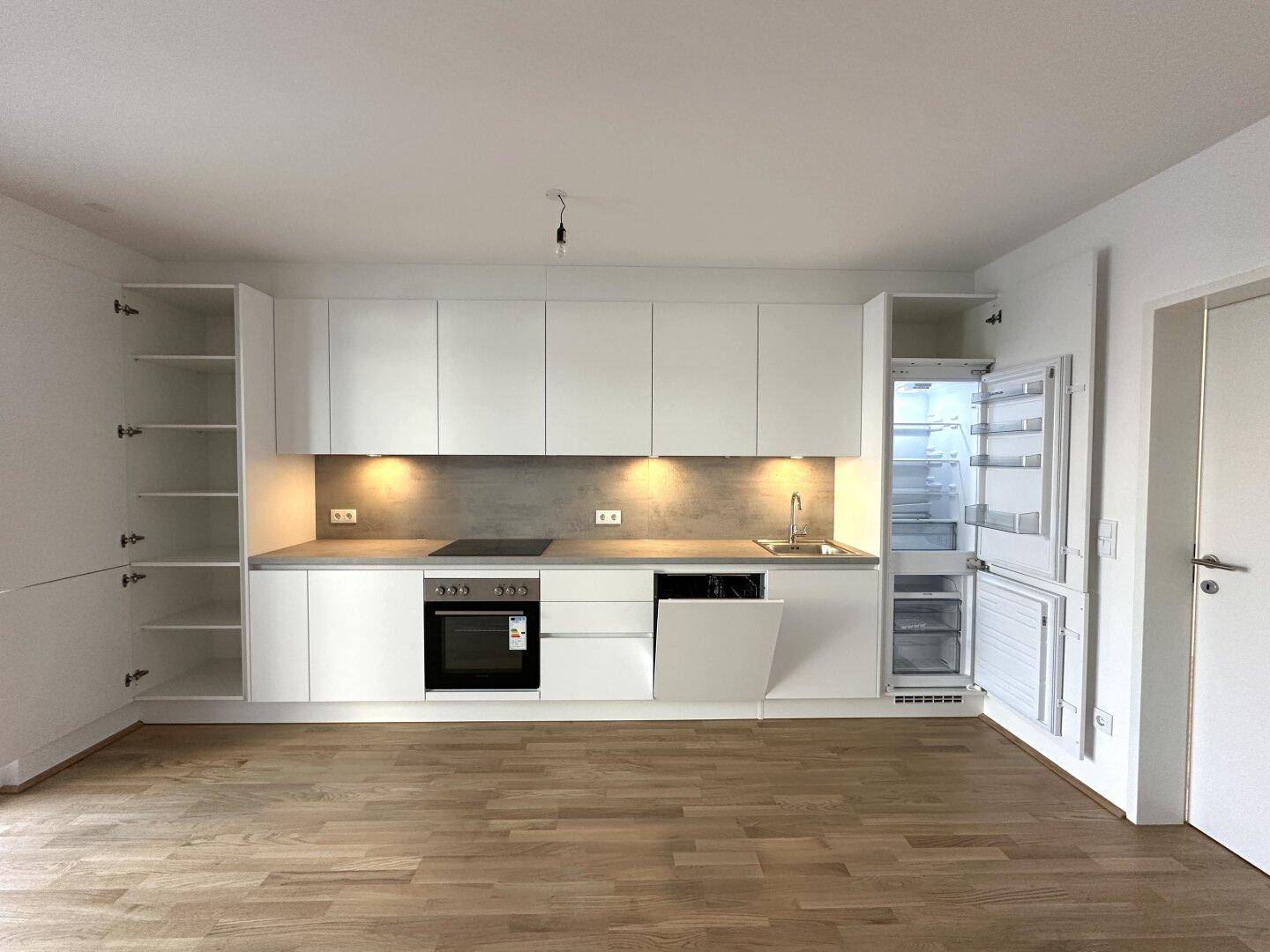 Voll ausgestattete, moderne Küche mit weißen Schränken, Kühlschrank und Geschirrspüler.