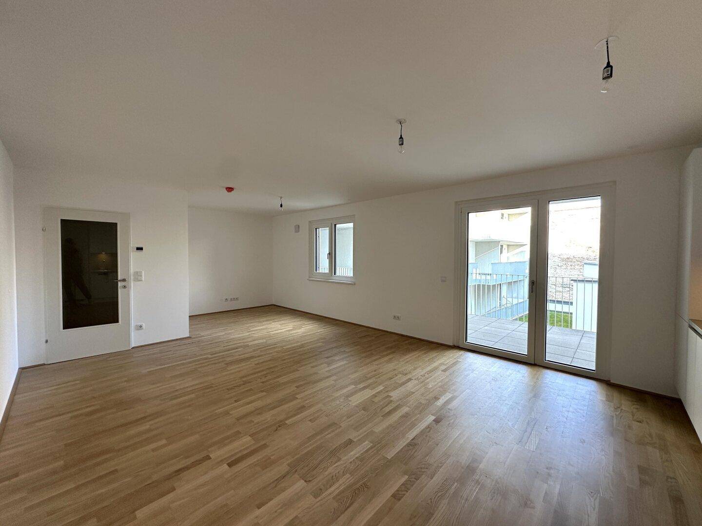 Lichtdurchfluteter Wohnbereich mit Holzboden und breiter Schiebetür zum Außenbereich.