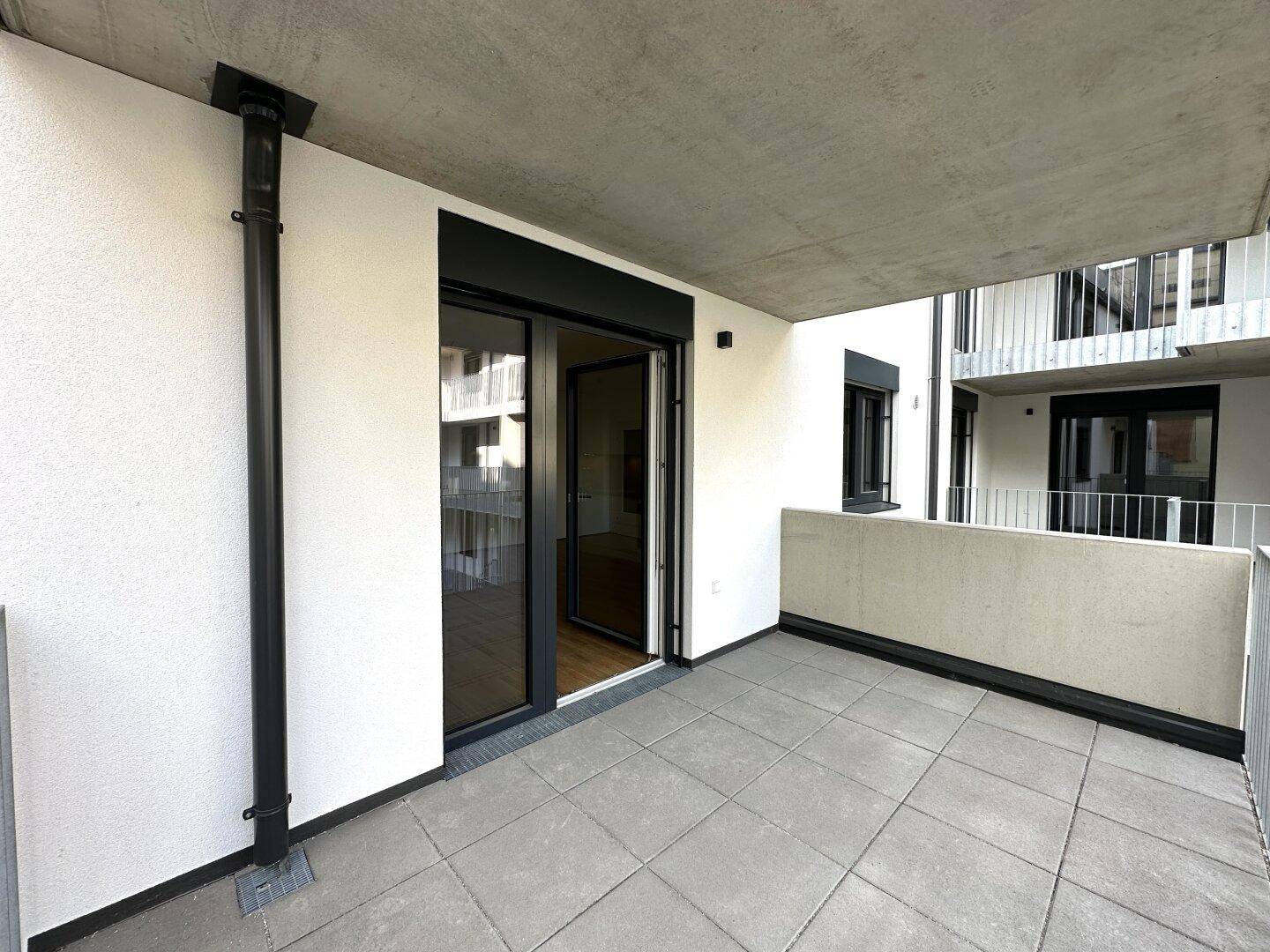 Überdachter Balkon mit Fliesenboden und Zugang zu den Innenräumen des Apartments.