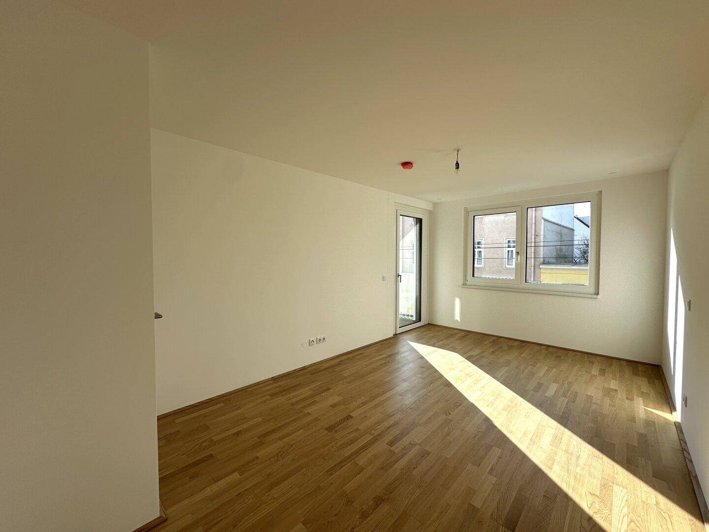 Helles Schlafzimmer mit Holzboden und Zugang zu einem französischen Balkon.