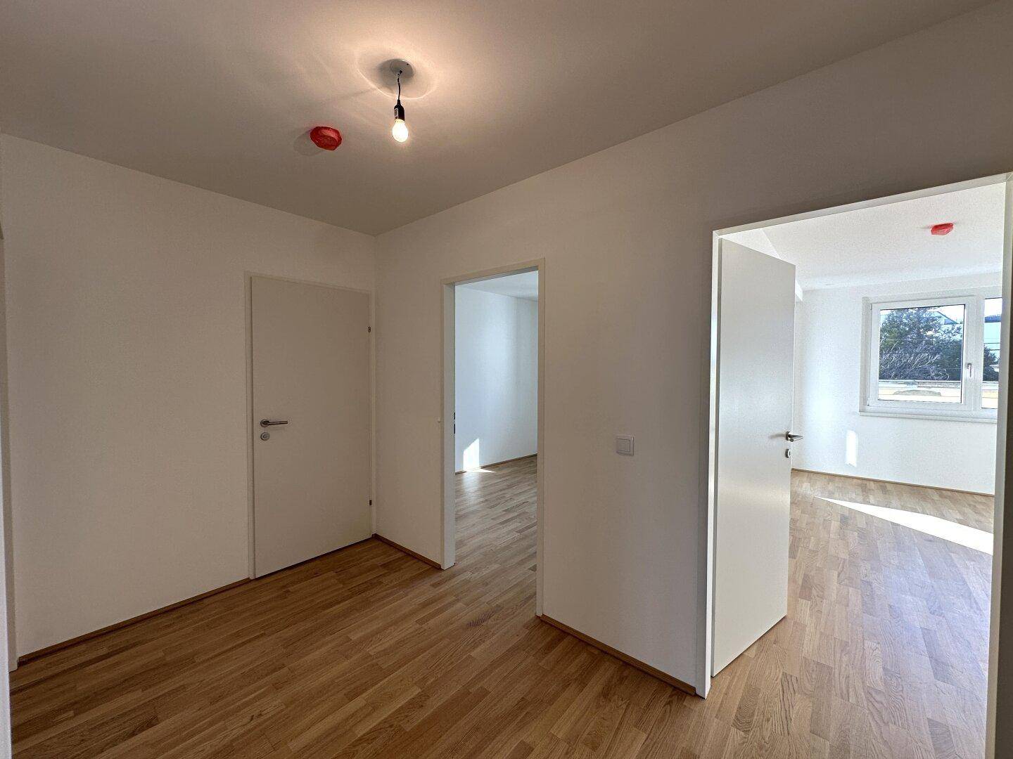 Flur mit hellem Parkettboden, der zu verschiedenen Zimmern des Apartments führt.