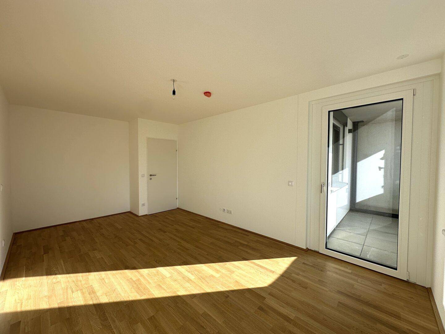 Geräumiges Schlafzimmer mit Parkettboden und bodentiefem Fenster für viel Tageslicht.