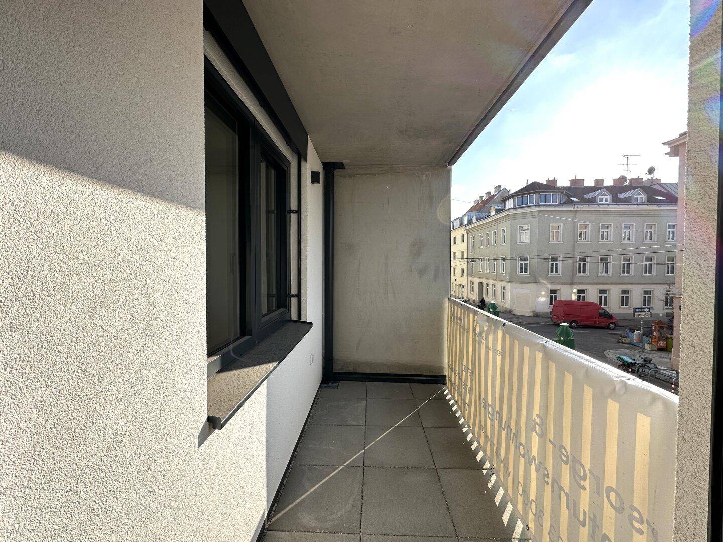 Schmaler Balkon mit Blick auf die Straße und die umliegenden Gebäude der Stadt.