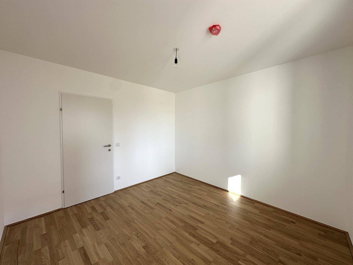 Modernes Schlafzimmer mit Parkettboden und weißer Tür, bereit zur individuellen Gestaltung.