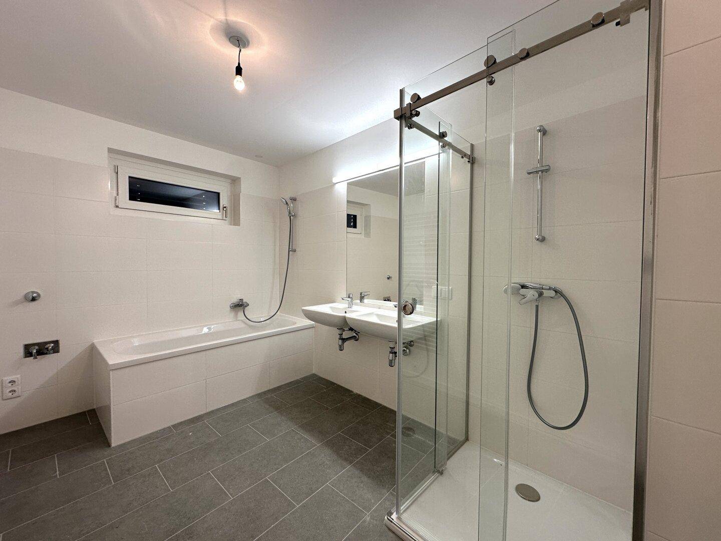 Geräumiges Badezimmer mit Badewanne, begehbarer Dusche und Doppelwaschbecken.