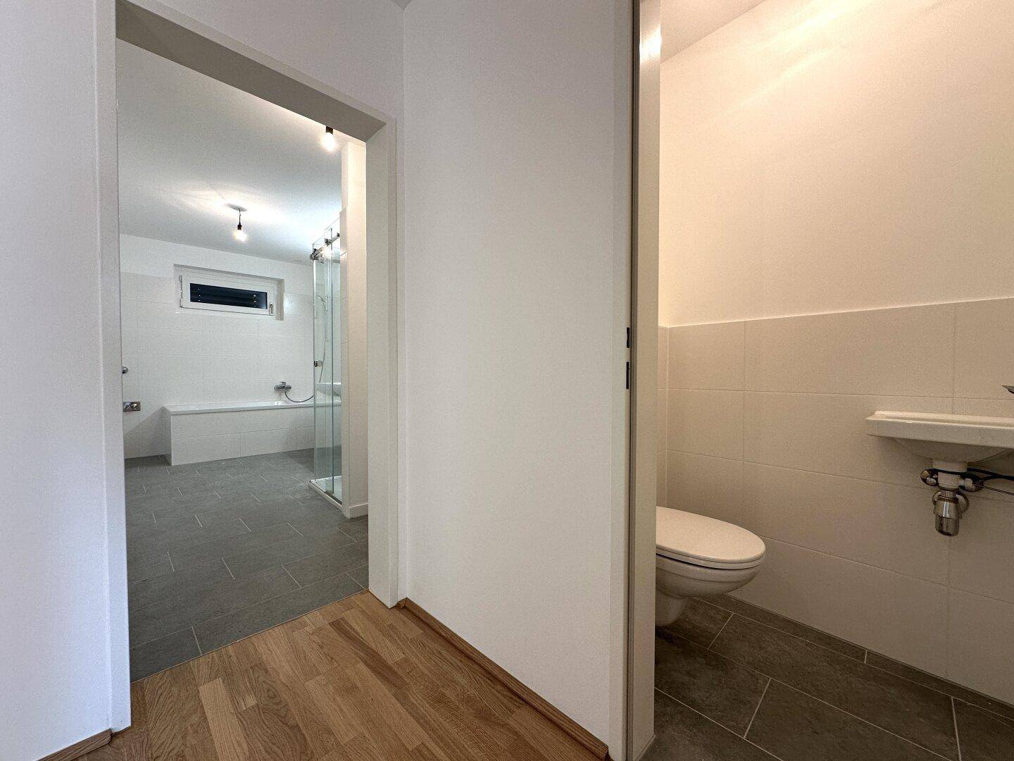 Flur mit Parkettboden, der zum Hauptbadezimmer und einem separaten WC führt.