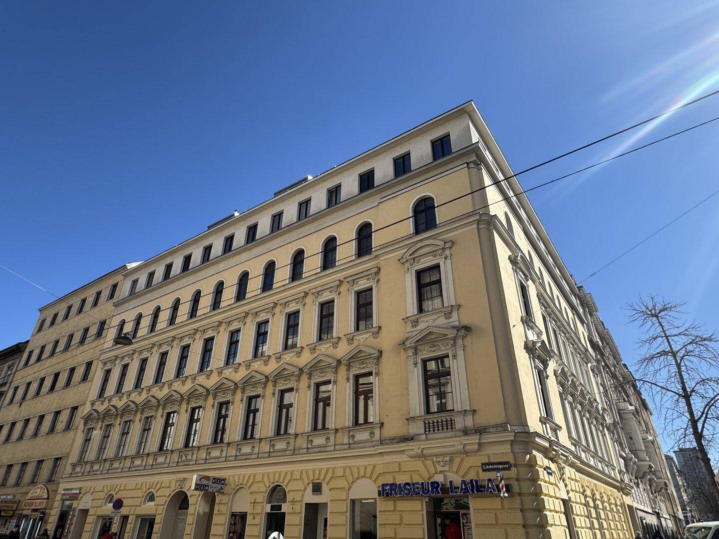 Städtisches Wohngebäude mit historischer Fassade und sonnigem Ausblick auf die Straße.