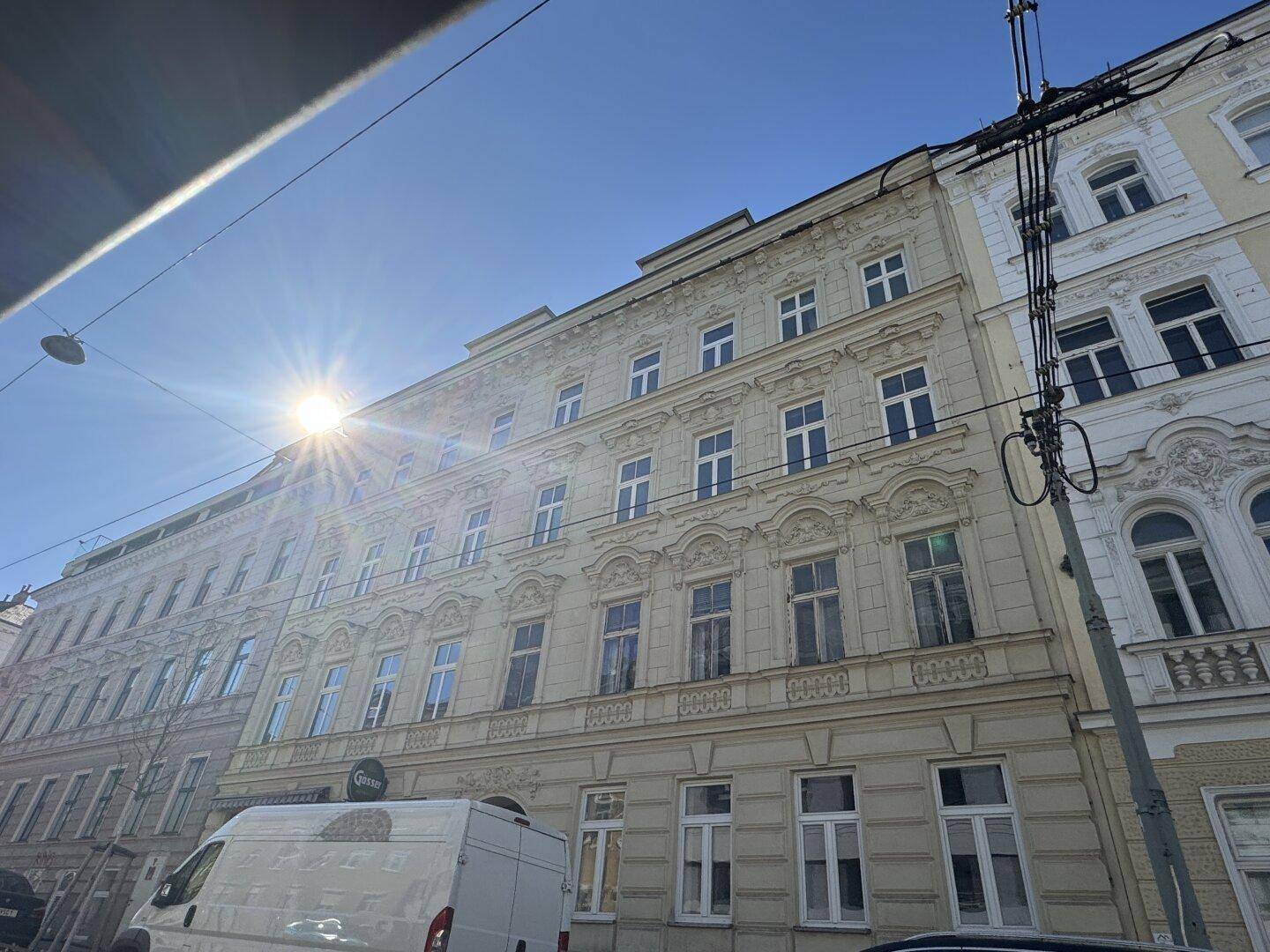 Stilvolles Mehrfamilienhaus mit Stuckfassade und großen Fenstern, aufgenommen an einem sonnigen Tag.