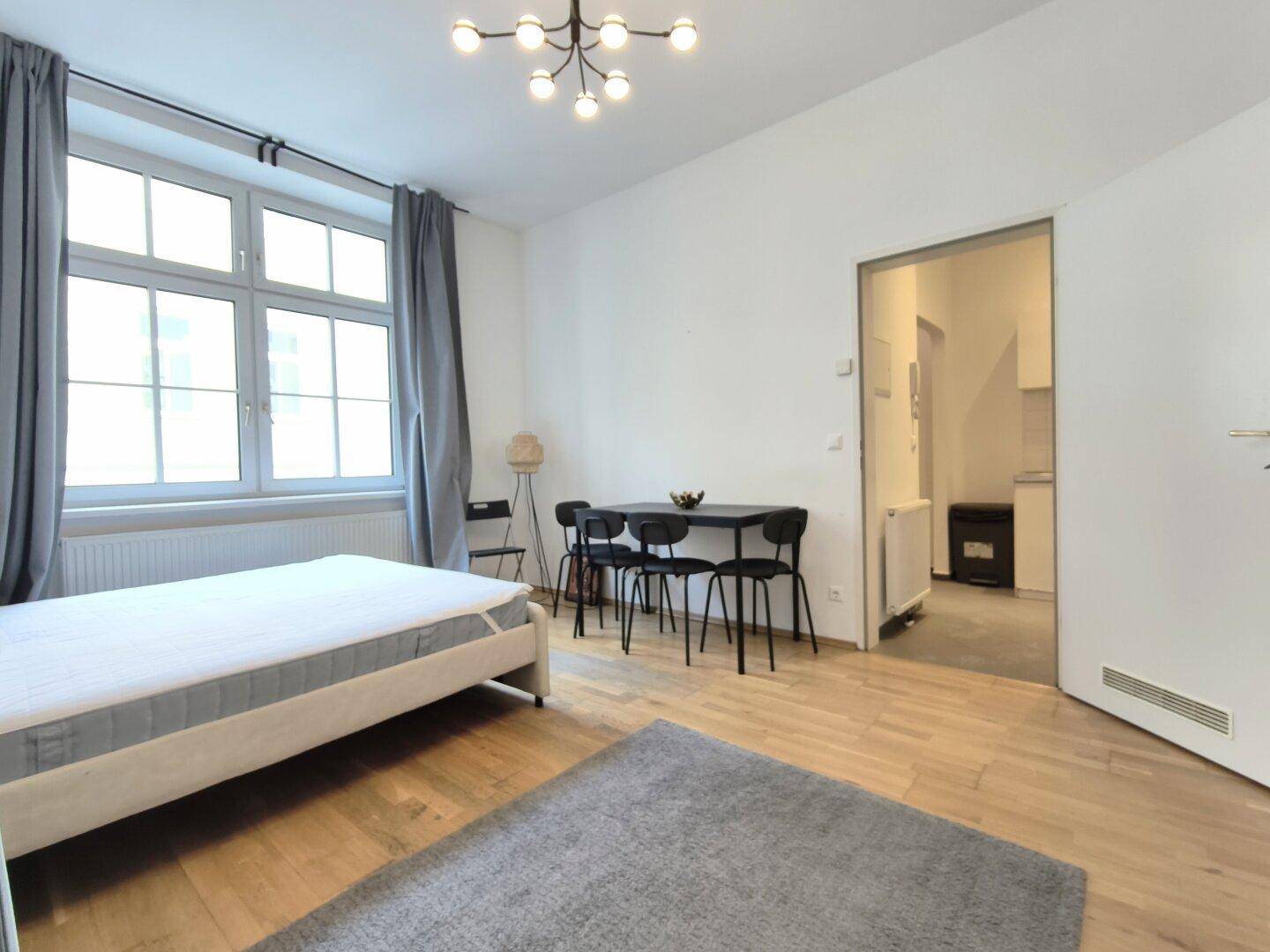 Geräumiges Studio-Apartment mit Schlafbereich, Essplatz und Zugang zur Kochnische.