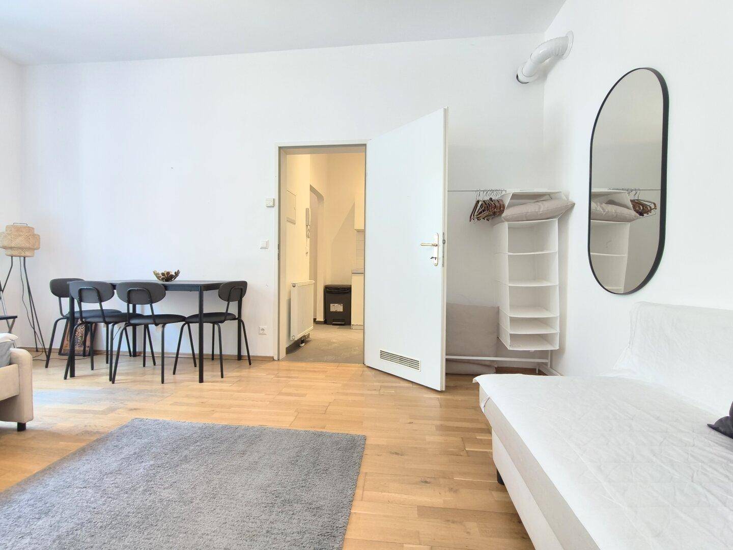 Studio-Apartment mit Essbereich, offener Tür zur Kochnische und Garderobenlösung.