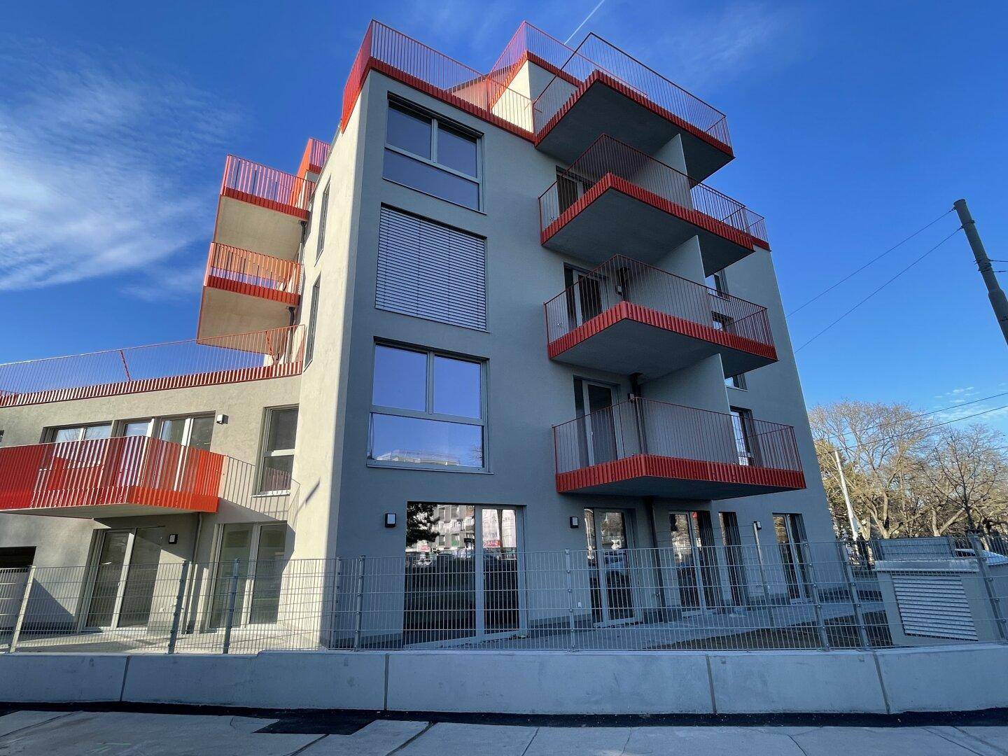 Modernes Mehrfamilienhaus mit auffälligen roten Balkonen und zeitgenössischer Architektur.