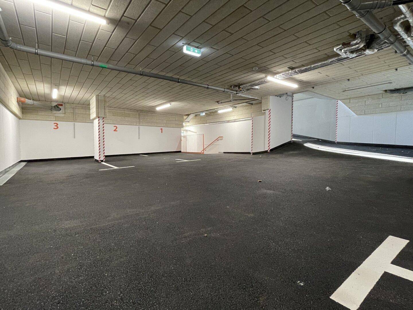 Geräumige Tiefgarage mit nummerierten Stellplätzen und sauberem Asphaltboden.
