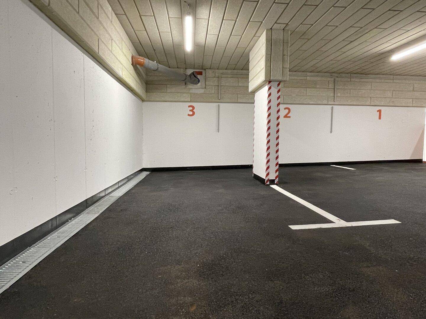 Saubere Tiefgarage mit markierten Parkplätzen und guter Beleuchtung.