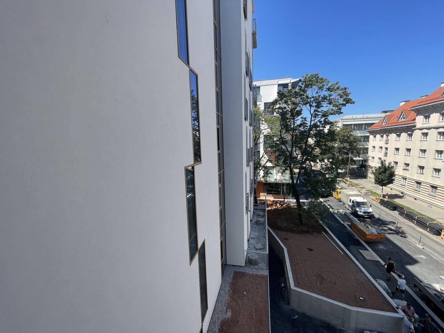 Seitenansicht eines modernen Wohngebäudes mit Blick auf die Straße und umliegende Bebauung.