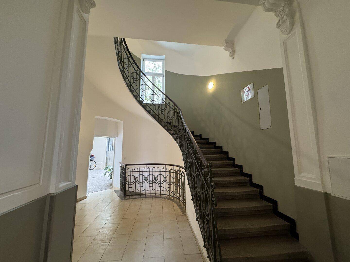 Prunkvoller Eingangsbereich mit einer eleganten geschwungenen Treppe und kunstvollen Verzierungen an den Wänden.