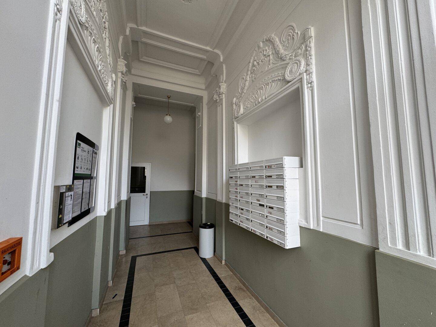 Repräsentativer Eingangsbereich mit Stuckdecken, Briefkästen und zweifarbigen Wänden in einem Altbau.