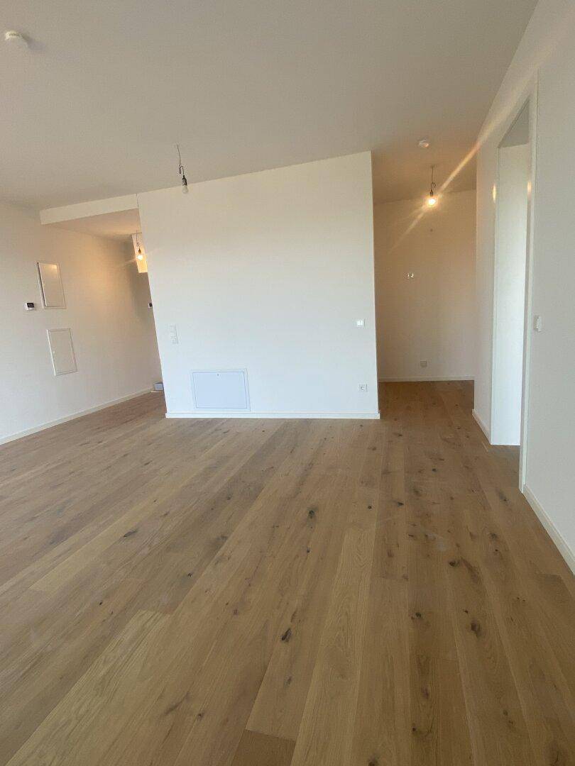 Heller, leerer Wohnbereich mit neuem Holzboden und weißen Wänden, bereit zum Einzug.