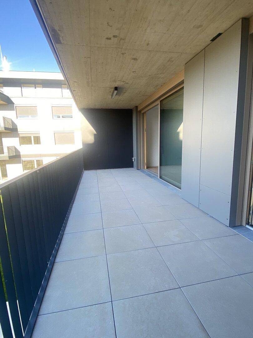Geräumiger Balkon mit Fliesenboden und Blick auf die Umgebung, ideal für Entspannung im Freien.