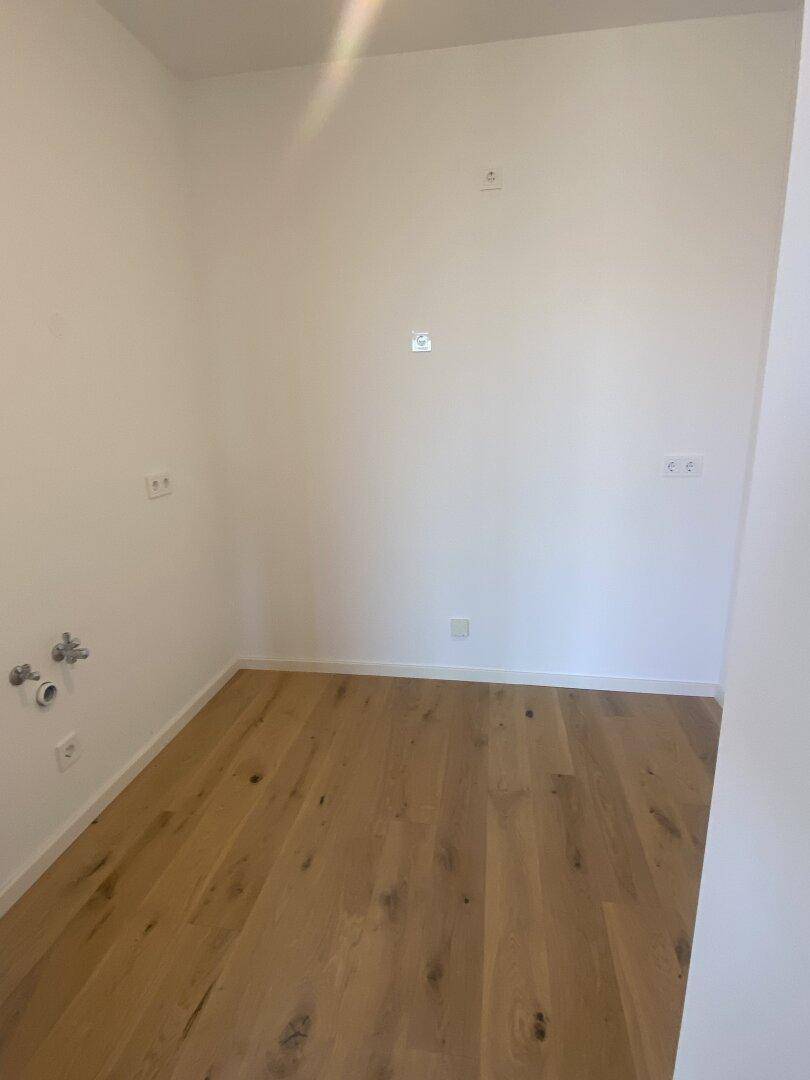 Kleiner Raum mit Holzboden und Anschlüssen an der Wand, ideal als Hauswirtschaftsraum.