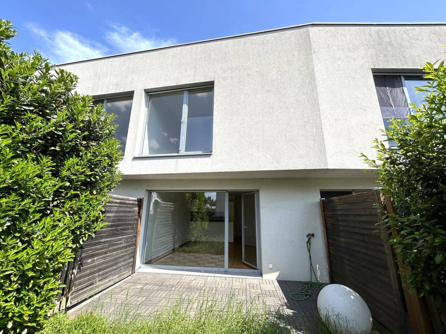 Hinterer Bereich des Hauses mit gepflasterter Terrasse und Zugang zum kleinen Garten.
