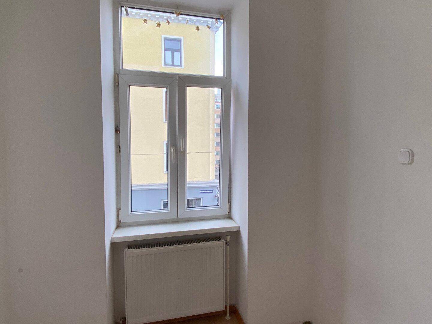 Heller Innenraum mit einem Fenster, das Tageslicht hereinlässt, und einem Heizkörper darunter.