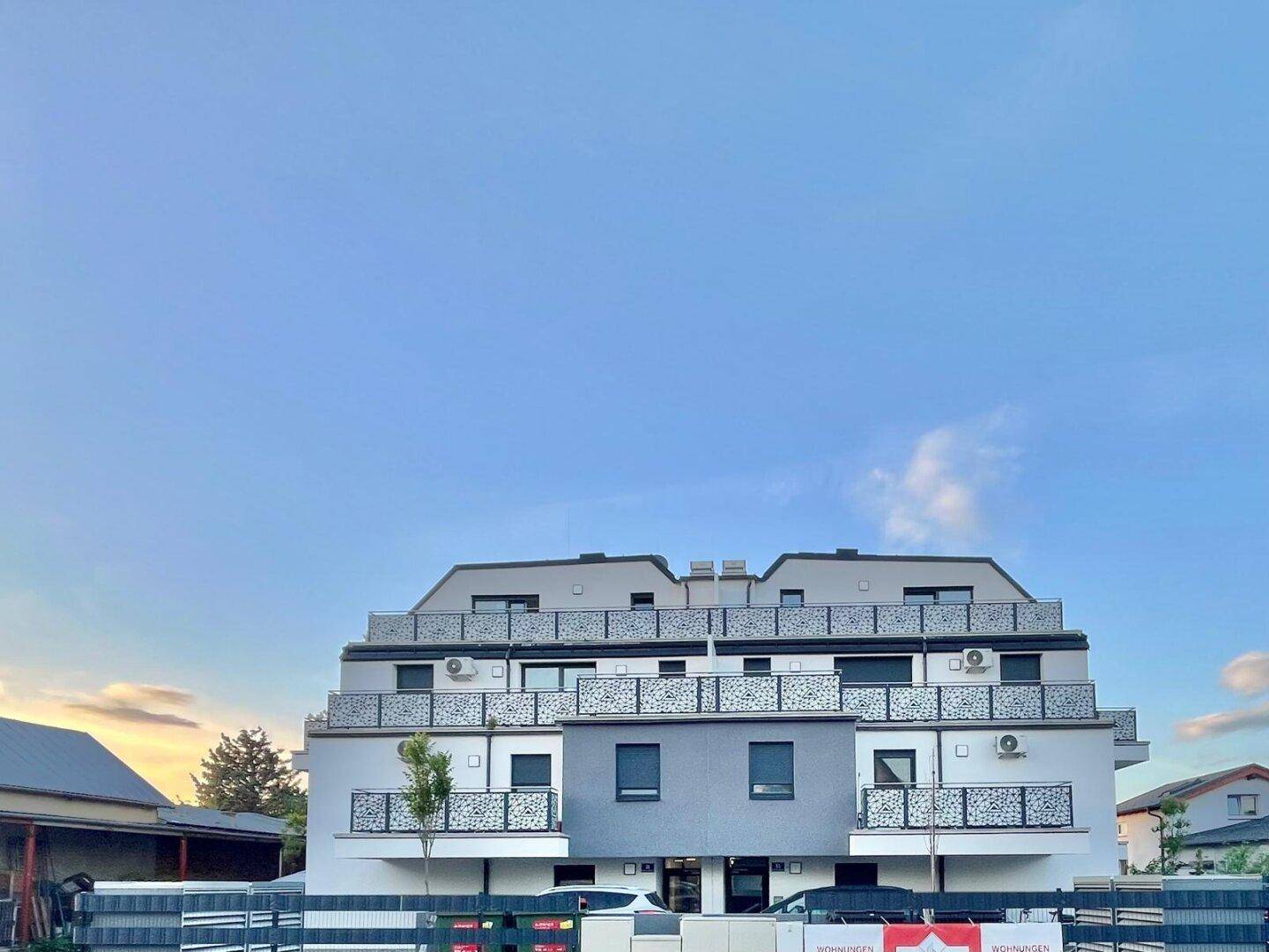 Moderne Fassade eines Mehrfamilienhauses mit mehreren Etagen und stilvollen Balkonen.