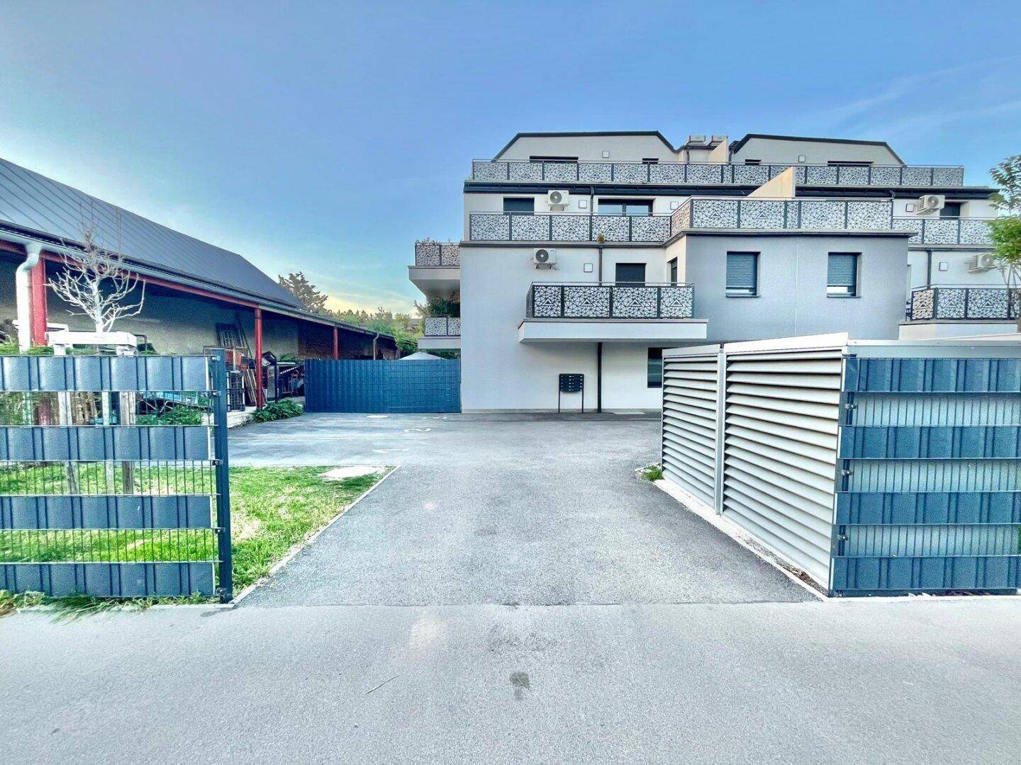 Zufahrt zu einem modernen Mehrfamilienhaus mit Balkonen und dekorativen Geländern.