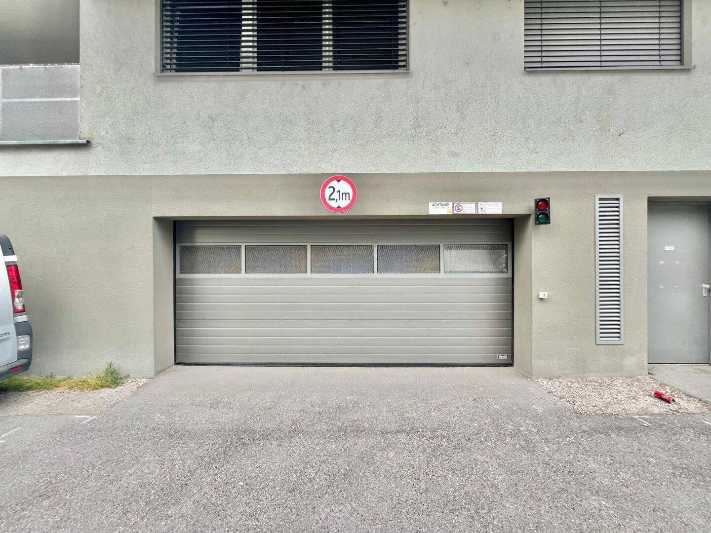 Eingang zu einer Tiefgarage mit geschlossenem Tor und Höhenbegrenzung von 2,1 Metern.