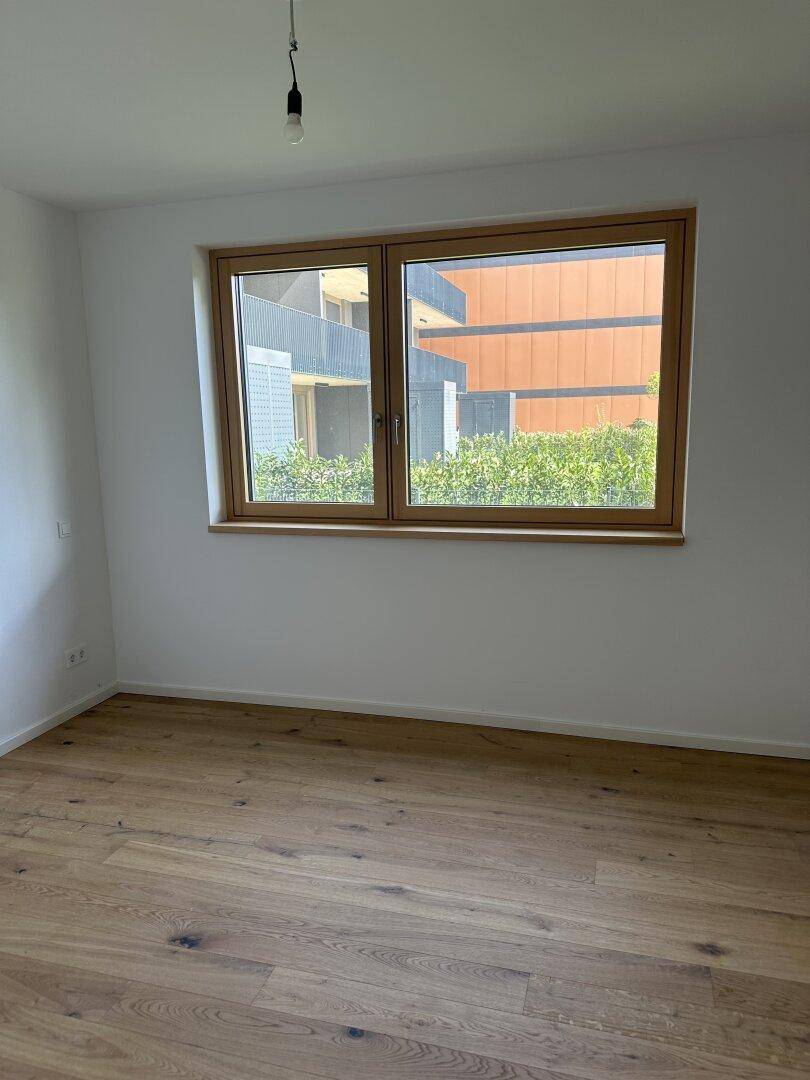 Geräumiges Schlafzimmer mit hellem Eichenparkett und einem großen Fenster für viel Tageslicht.
