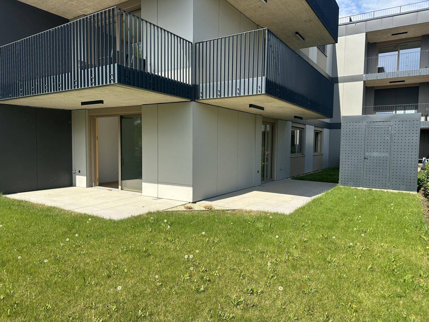 Erdgeschosswohnungen mit privaten Terrassen und direktem Zugang zu einer grünen Rasenfläche.