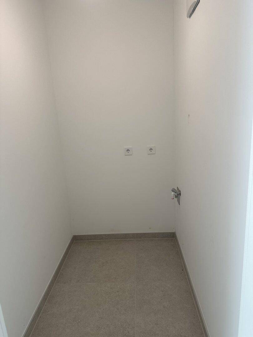 Kleiner Hauswirtschaftsraum mit Fliesenboden und Anschlüssen für Waschmaschine oder Trockner.