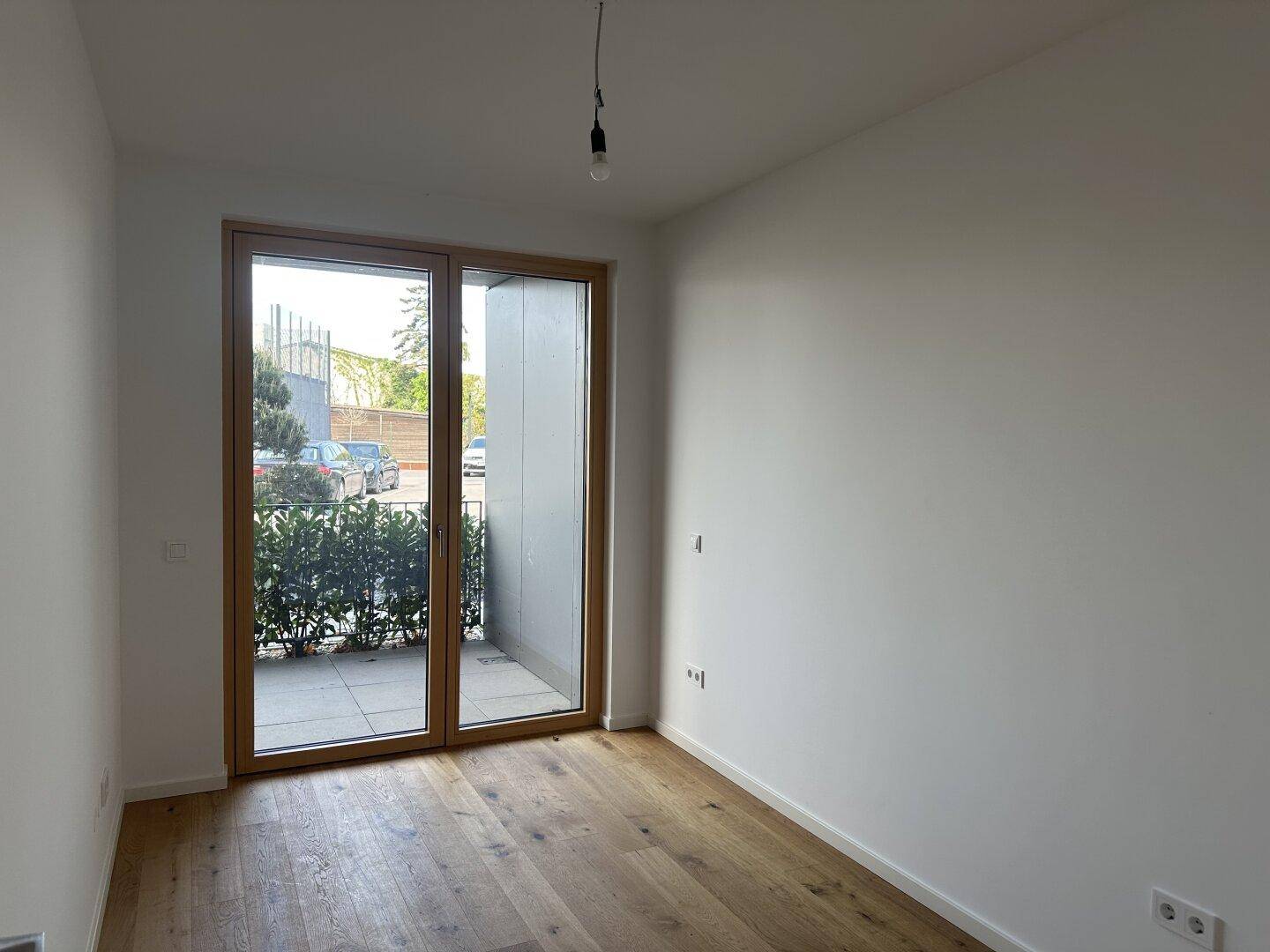 Helles Schlafzimmer mit Holzboden und Zugang zu einer kleinen Terrasse oder einem Balkon.