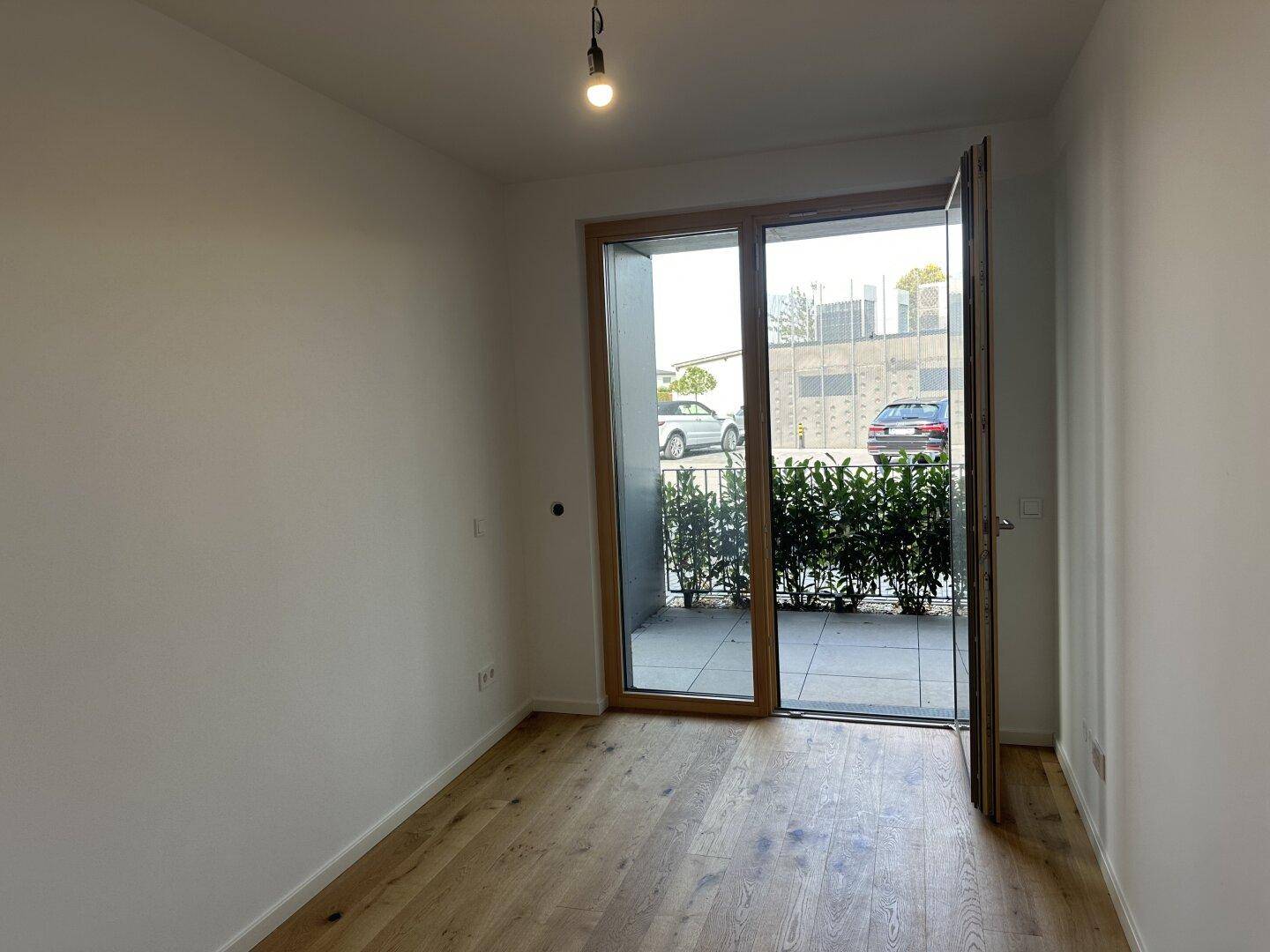Helles Schlafzimmer mit Holzboden und Zugang zu einer kleinen Terrasse oder einem Balkon.