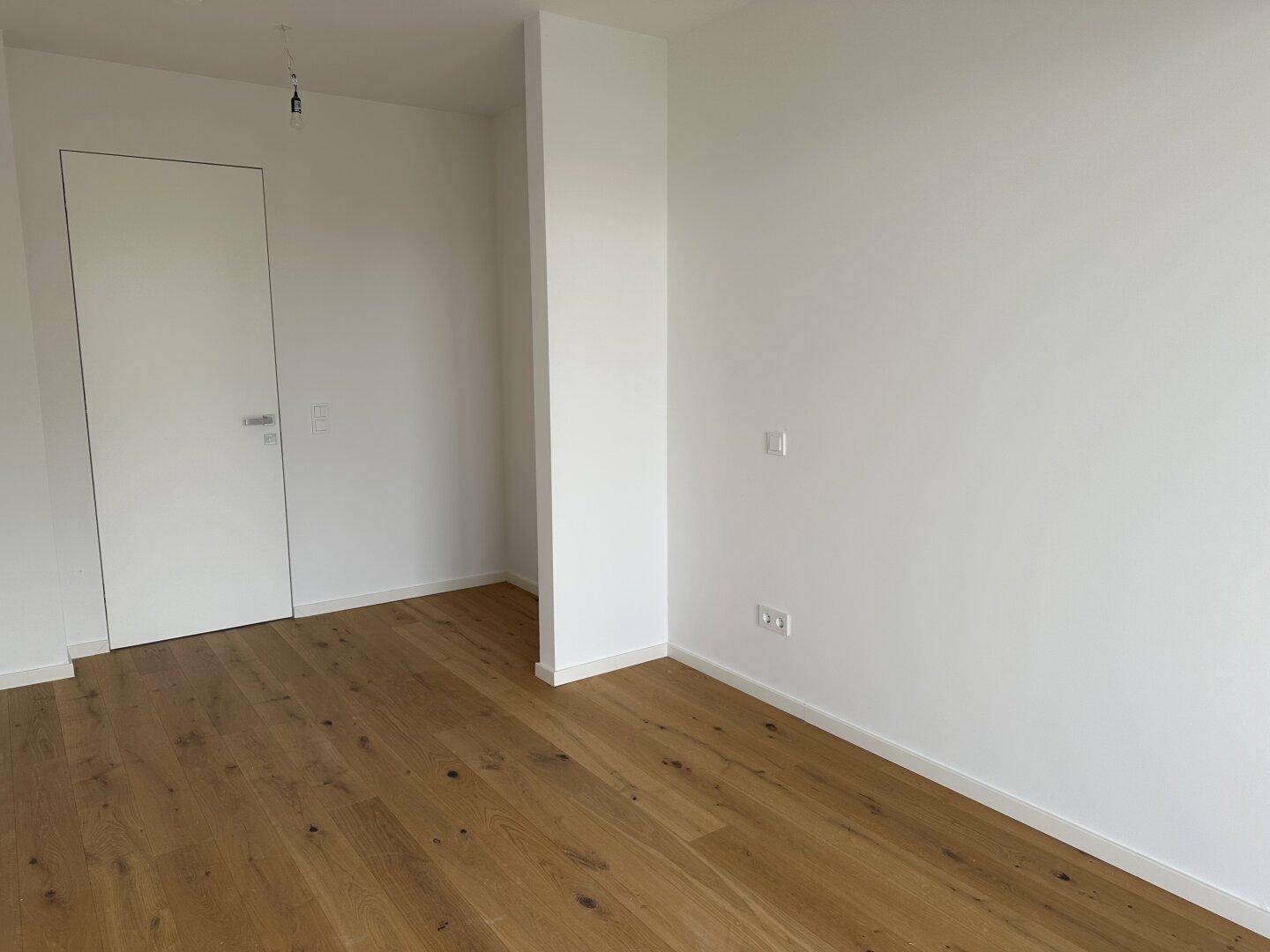 Helles Zimmer mit Eichenparkettboden und weißen Wänden, bereit zur individuellen Gestaltung.