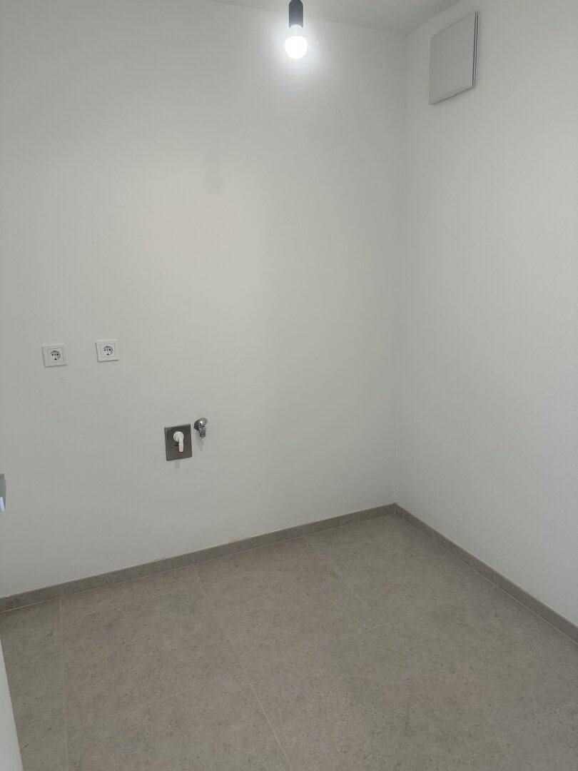 Praktischer Hauswirtschaftsraum mit Fliesenboden und Anschlüssen für Waschmaschine.