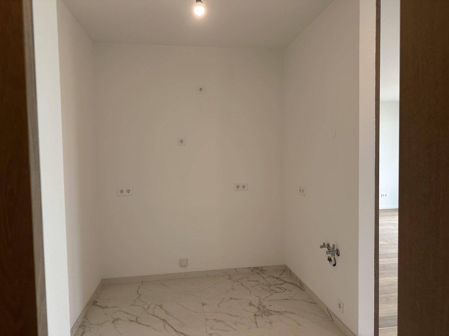 Praktischer Hauswirtschaftsraum mit Fliesenboden und Anschlüssen für Waschmaschine oder Trockner.