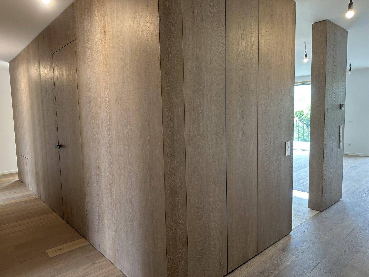 Moderner Flur mit eleganten Holzpaneelen und durchgehendem Holzplankenboden.