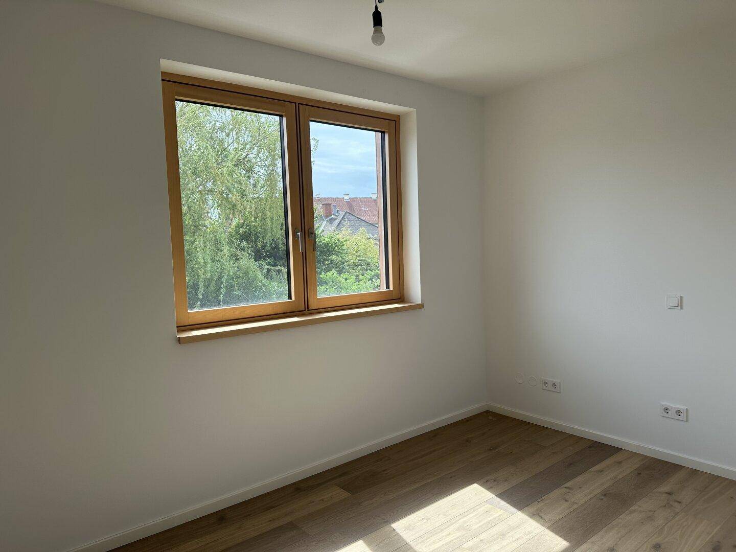 Geräumiges Schlafzimmer mit Holzplankenboden und einem großen Fenster für viel Tageslicht.