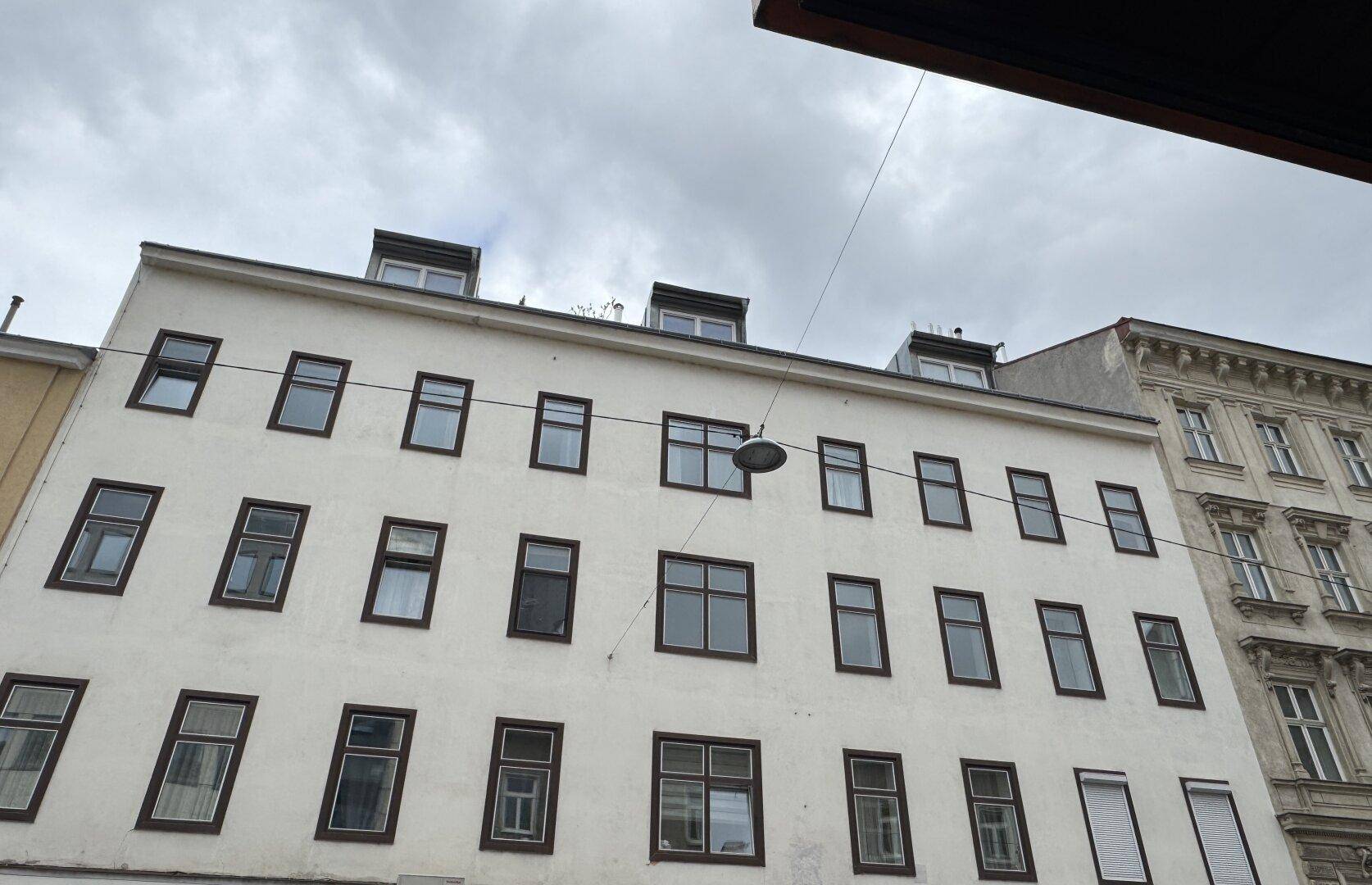 Fassade eines älteren Gebäudes mit zahlreichen Fenstern und Dachgauben, aufgenommen aus leicht verändertem Winkel.