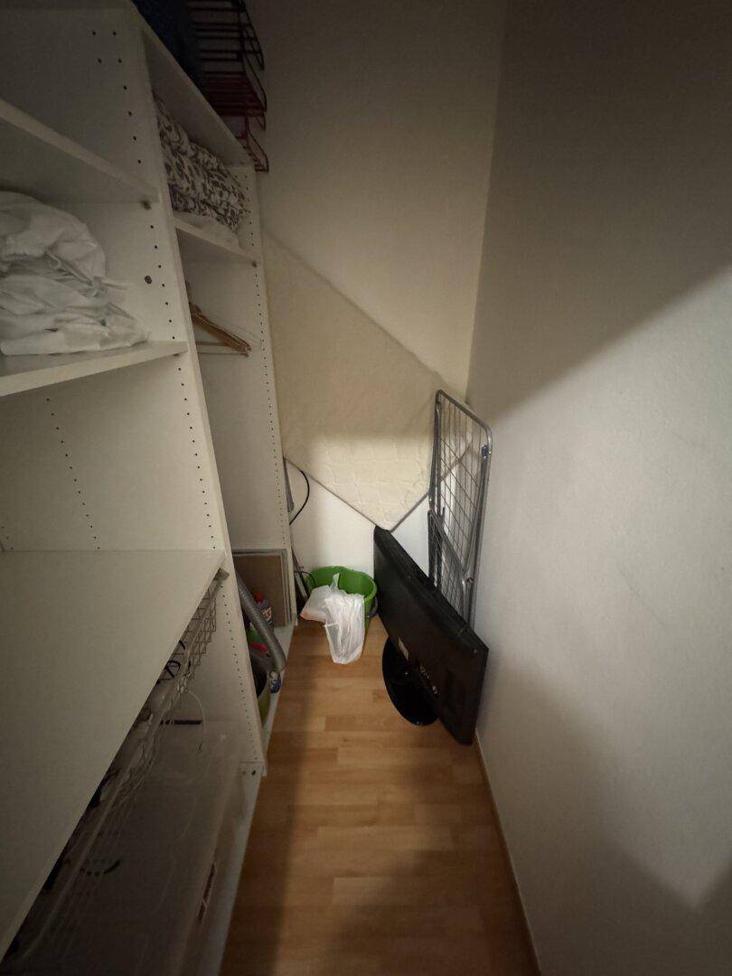 Schmaler Abstellraum mit Regalen und Stauraum unter einer Dachschräge.