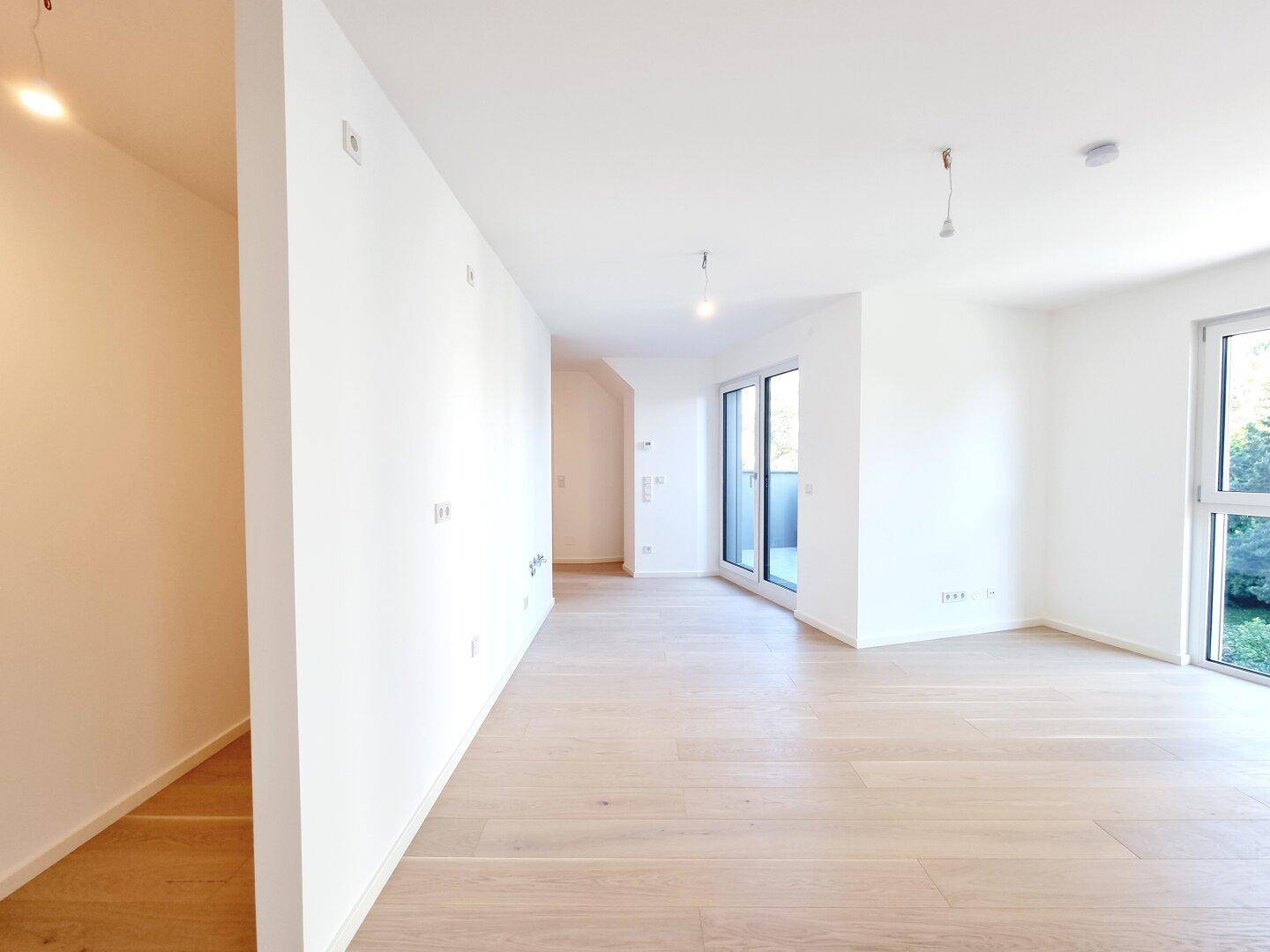 Heller, offener Wohnbereich mit Holzboden und großen Fenstern, die viel Tageslicht hereinlassen.