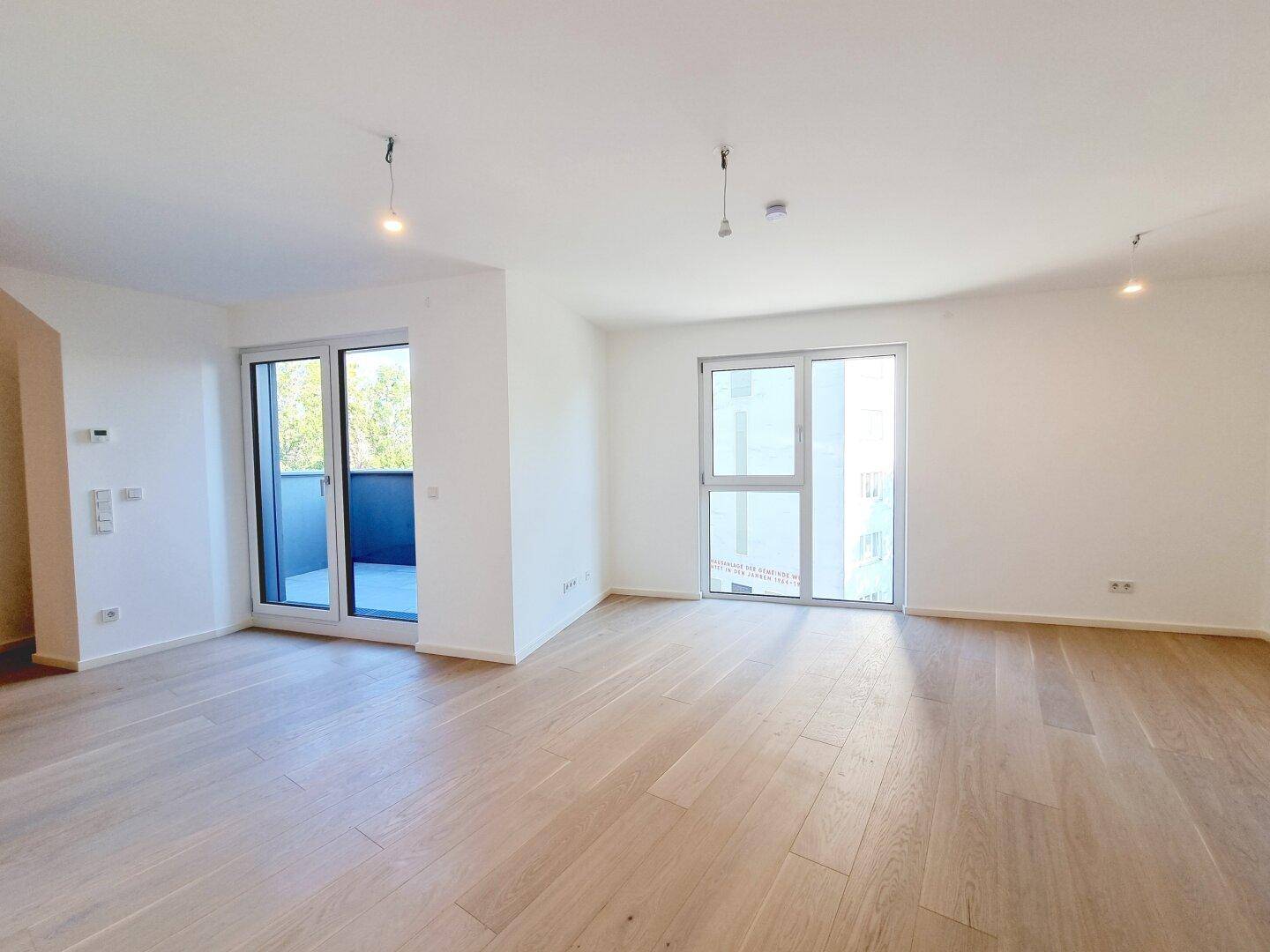 Heller Wohnbereich mit Holzboden und großem Balkonzugang, der viel Licht und frische Luft bietet.