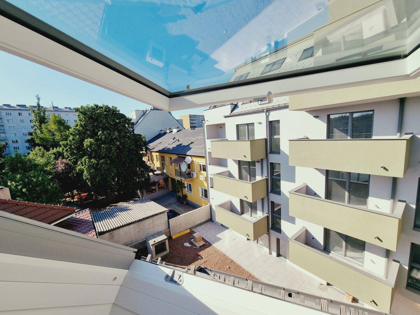 Blick aus einem Dachfenster auf einen Innenhof und die umliegenden Wohngebäude.