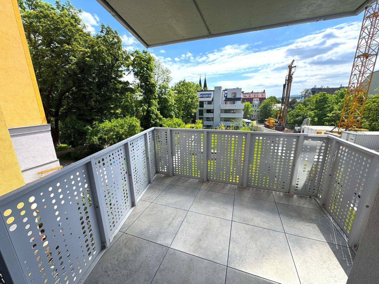 Geräumiger Balkon mit modernen Lochblechgeländern und Blick auf die Umgebung.