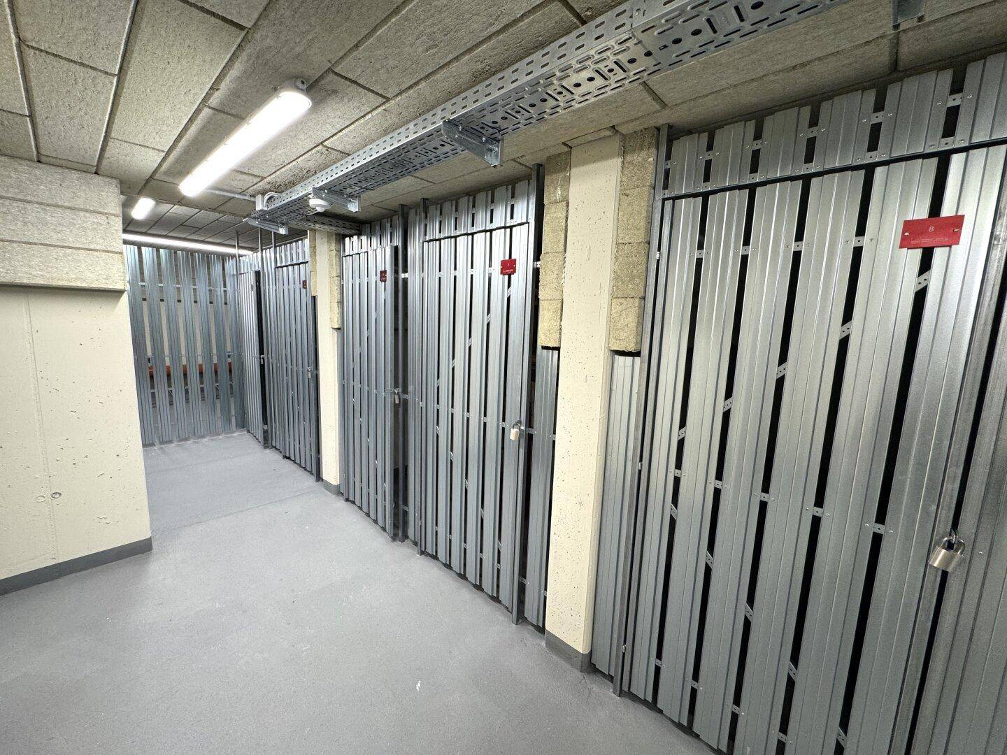 Kellerabteile mit Metalltüren und sichtbaren Installationen in einem gut organisierten Lagerbereich.
