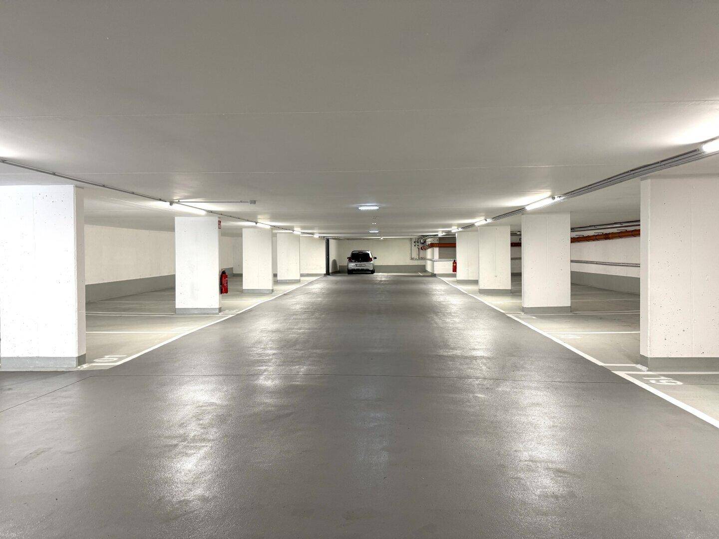 Geräumige und helle Tiefgarage mit vielen freien Stellplätzen und sauberem Betonboden.