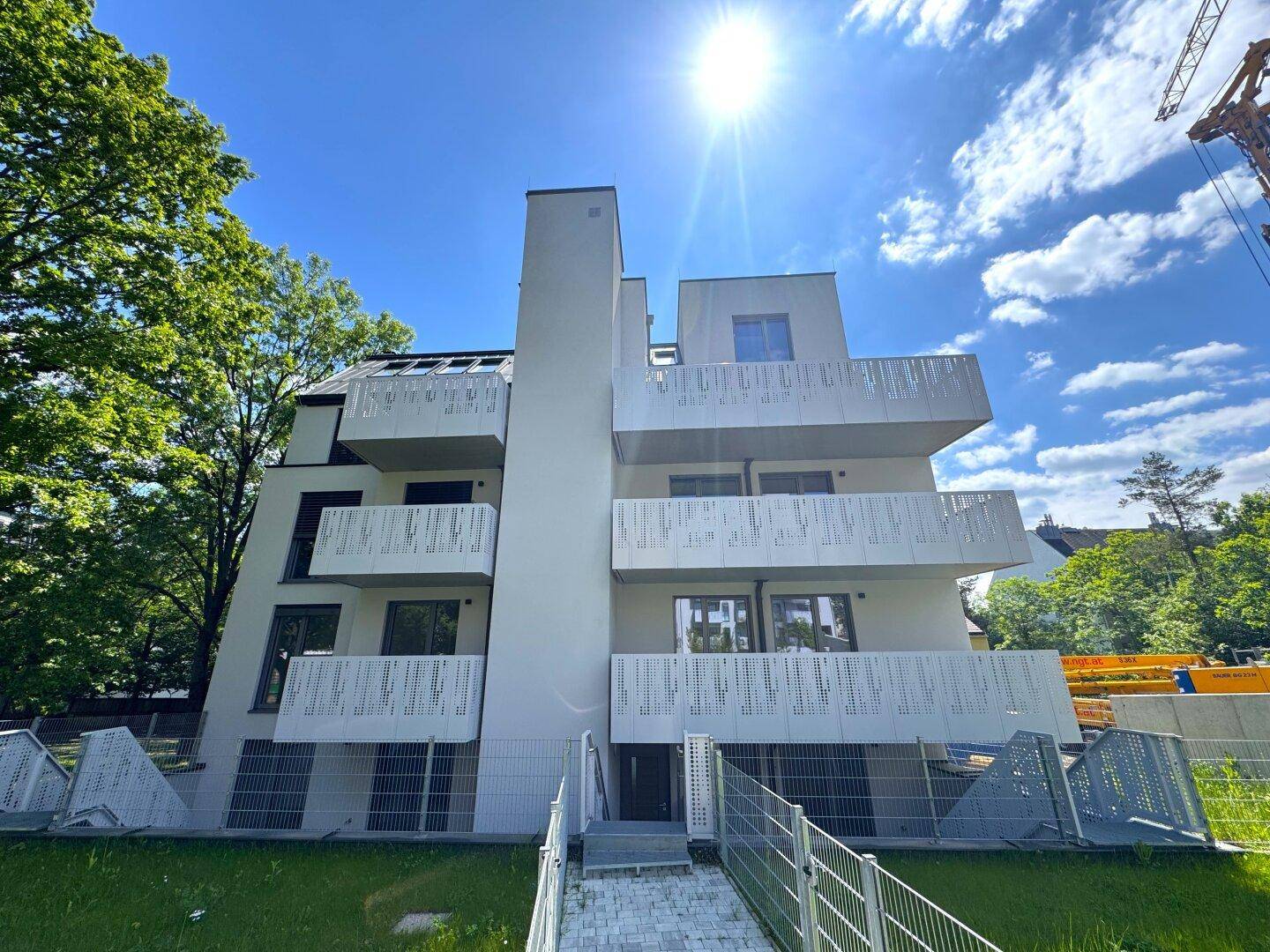 Die moderne Fassade des Apartmentgebäudes mit mehreren Balkonen und dekorativen Geländern im Sonnenlicht.